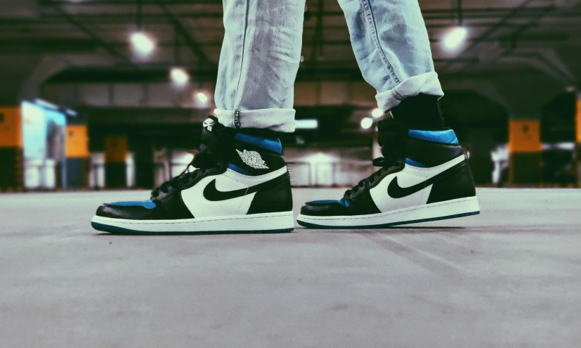 a man with grey pants and black shoes in a parking garage