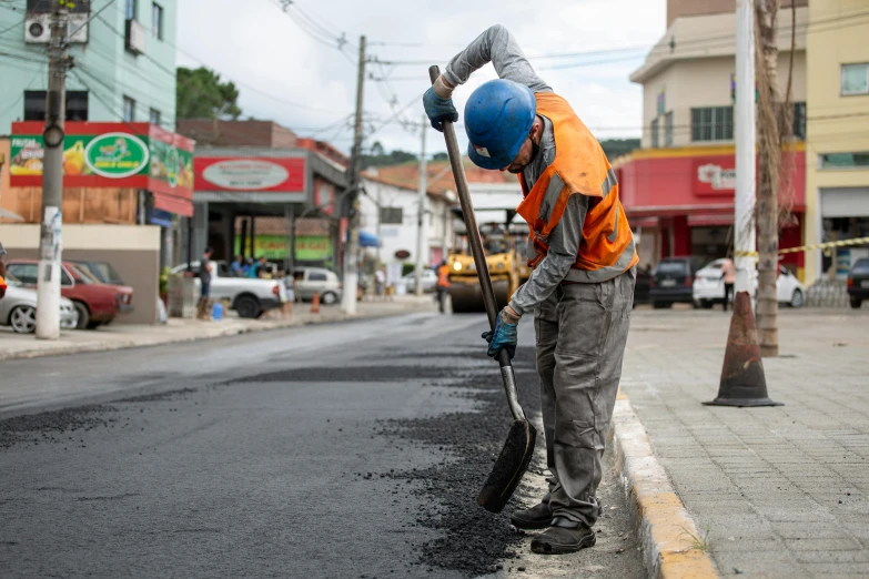 a worker is cleaning up a pot hole in the middle of a street