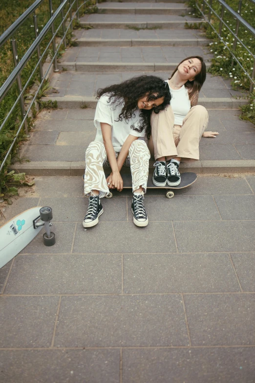two s sit on the ground while holding onto skate boards