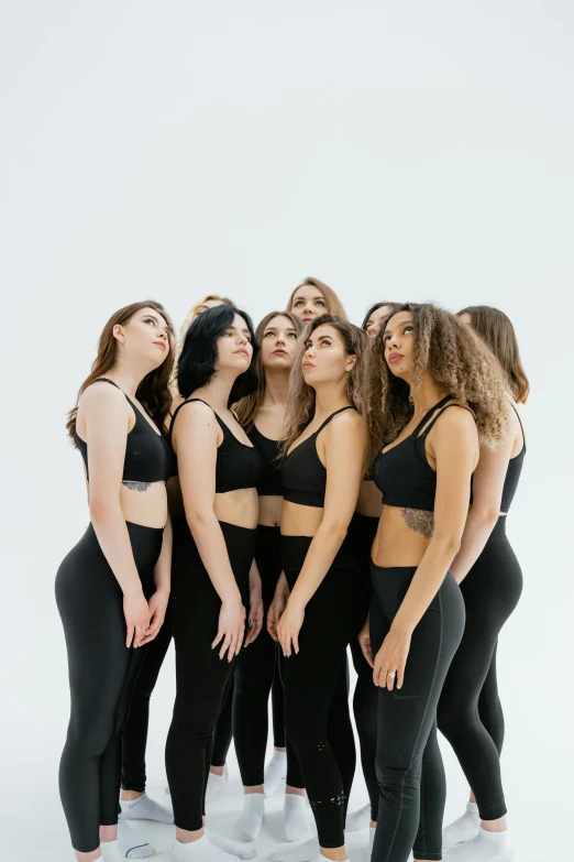 a group of women standing in a row, all wearing black outfits