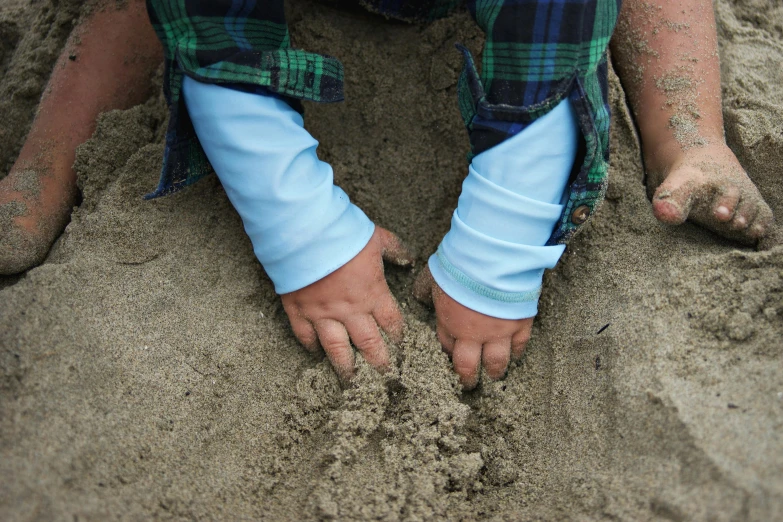 a person is sitting in the sand making footprints