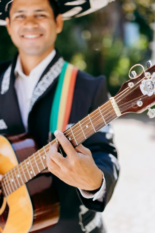 a man in black and white mexican attire playing a guitar