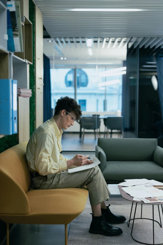 a man sitting on a chair looking at his laptop