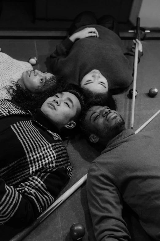 three young men lay on the ground while one man sits beside them