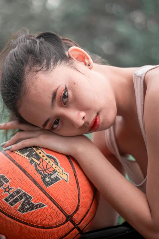 a beautiful young lady holding a basketball over her shoulder