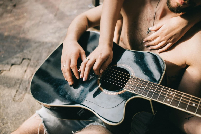 a man is holding a black acoustic guitar