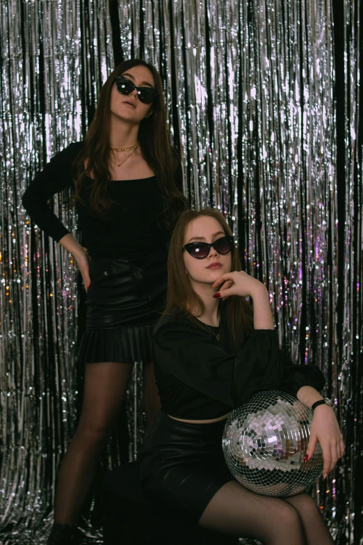 two women posing together in front of a silver background