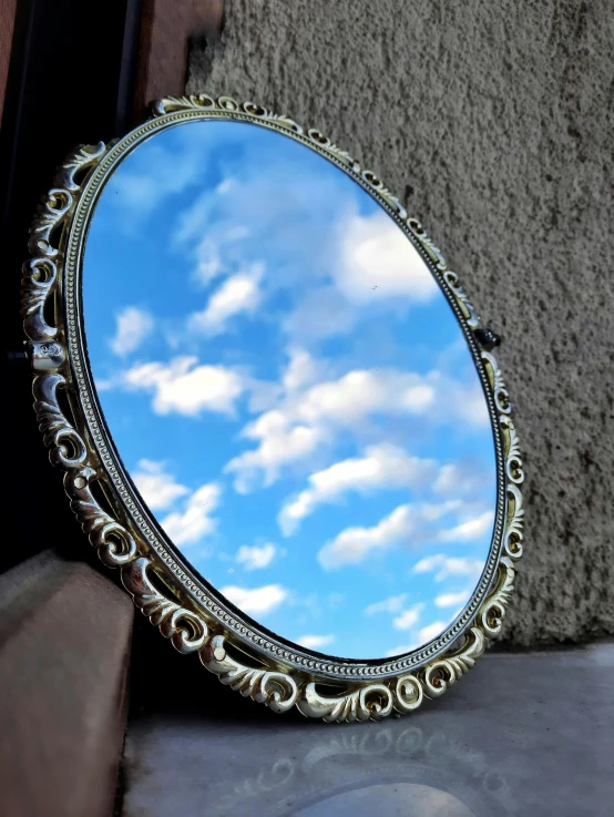 a mirror on a wall with clouds in the reflection