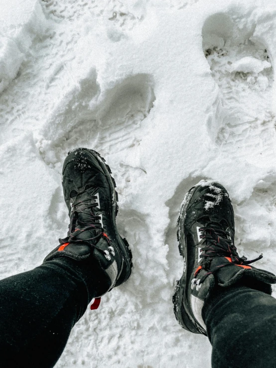 the man is standing in the snow with his feet up