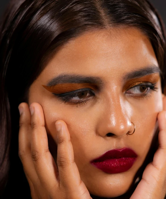 a girl has her hands on her face while she is putting on her makeup