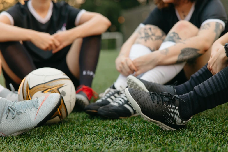 four people sitting next to each other on grass