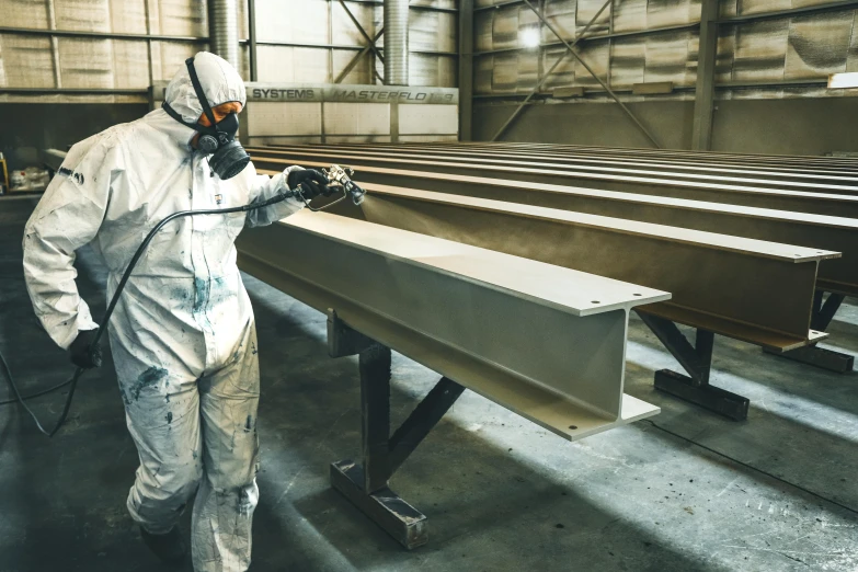 a man in a hazmat works on metal structure