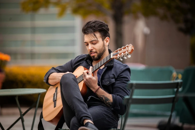 a man sitting on a chair playing an ukulele