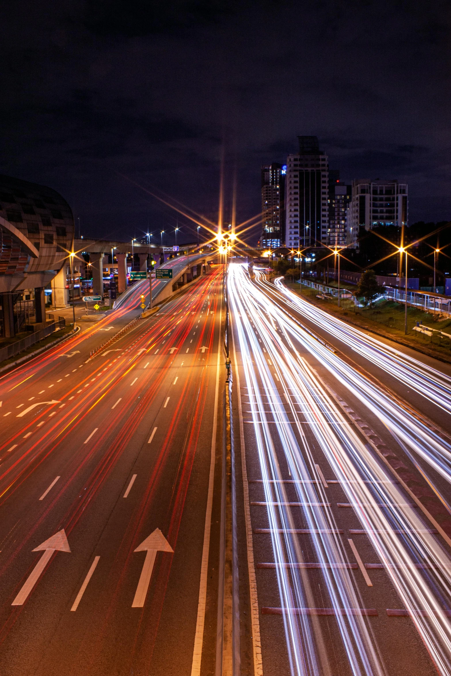 cars driving along highway at night with lights from buildings