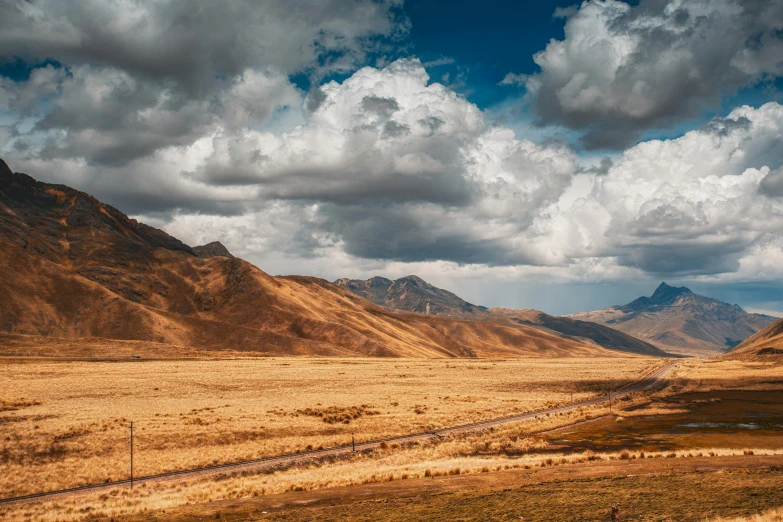 some mountains and grass with a sky in the background