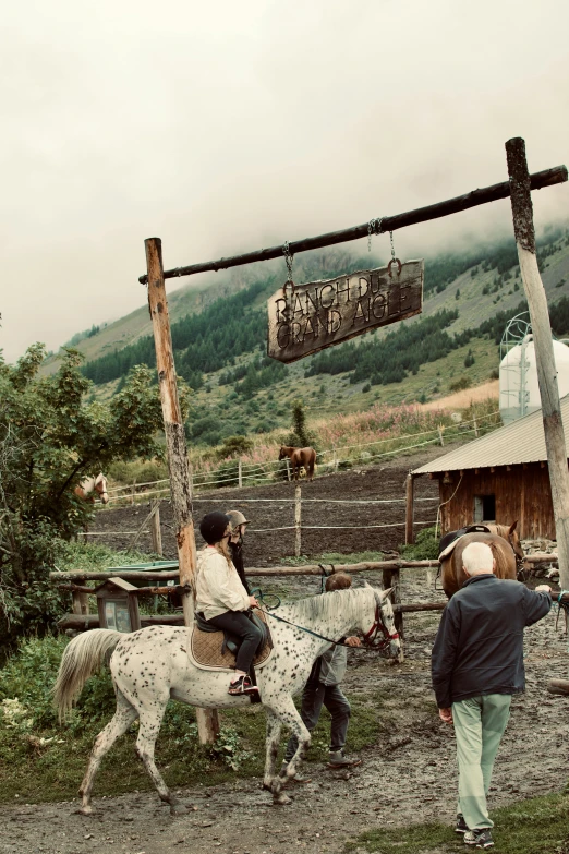 two people riding a horse at an enclosure