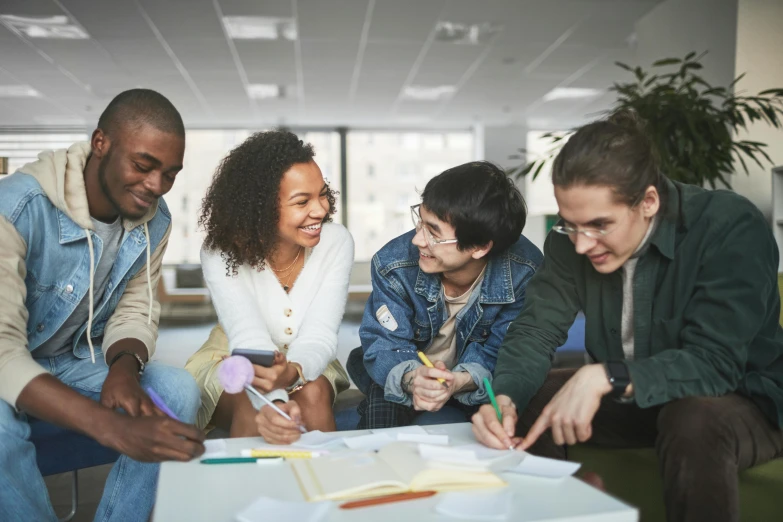 four students in an office gathered around a binder and paper