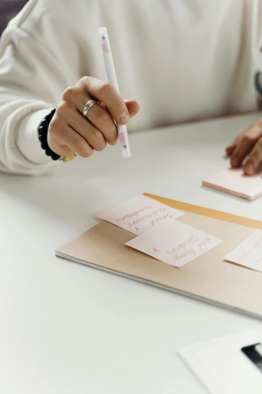 a person writing on papers and holding a pencil