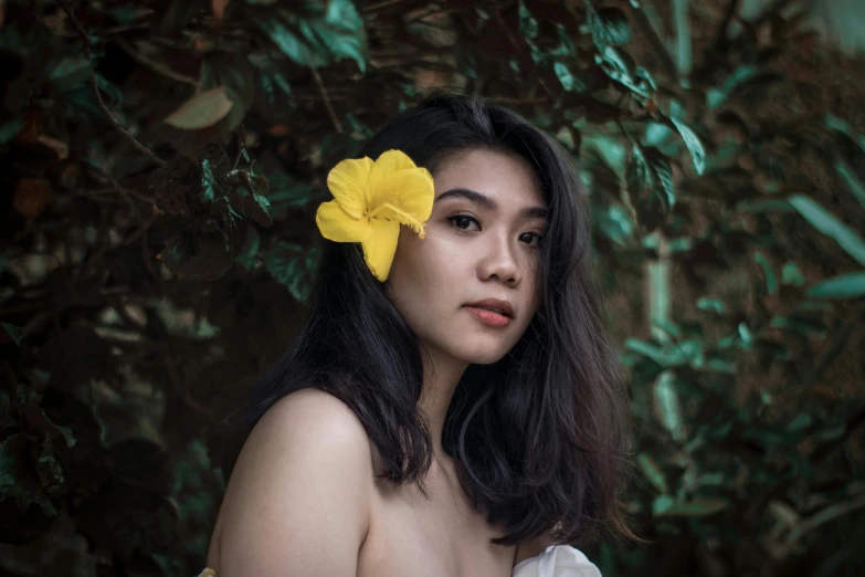 woman with yellow flower in her hair posing for po