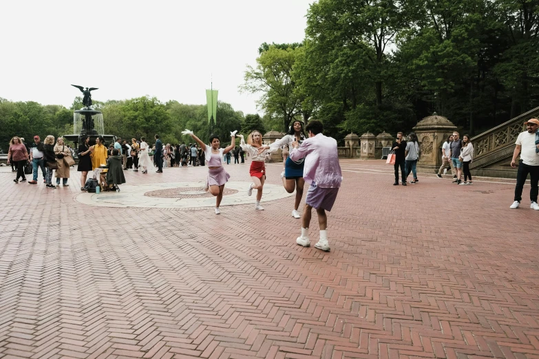 people walking on a street in front of an fountain