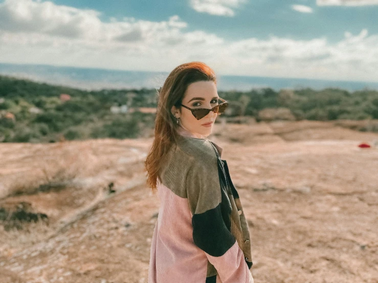 a woman in pink and black jacket and sunglasses standing outside