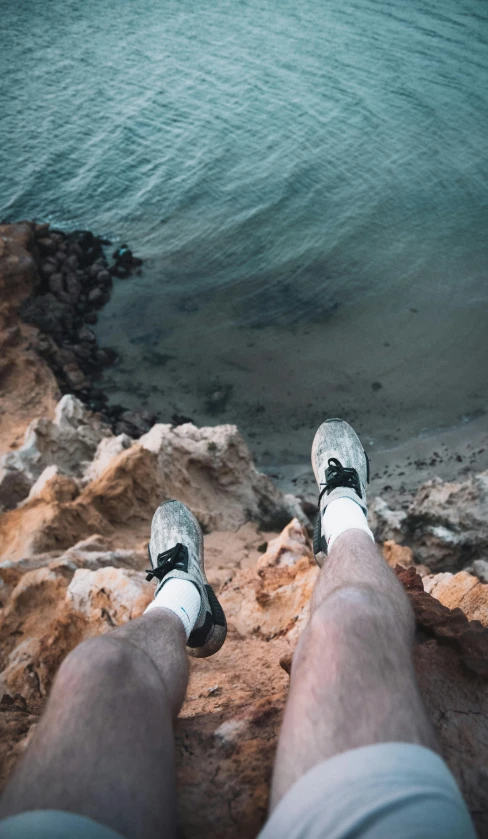 man's feet on a ledge over the water of a lake