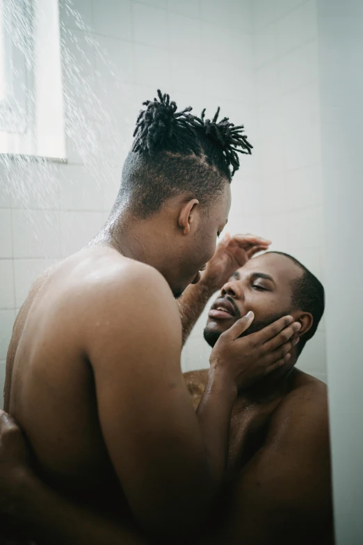 a man brushing his teeth while another looks in the mirror
