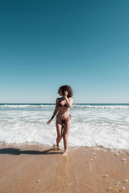 a woman with short hair walking on a beach