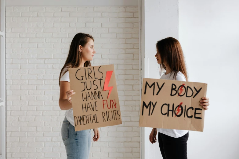 two girls holding signs reading my body is not choice
