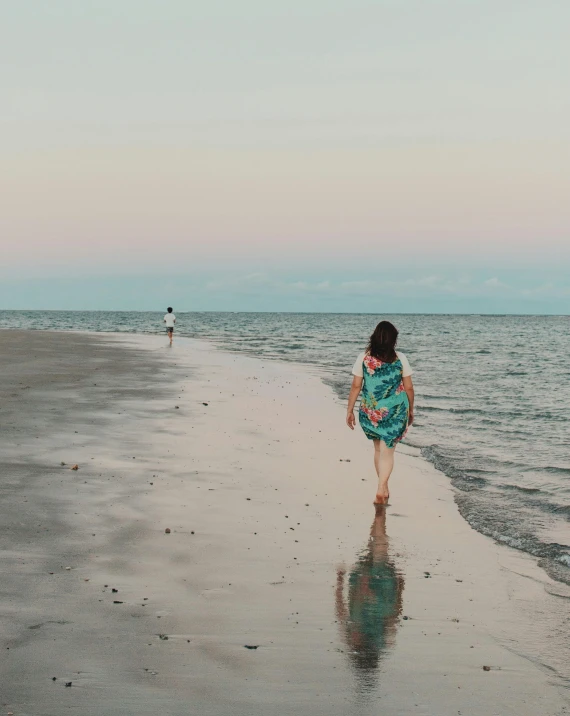 a girl is walking on the beach next to the water