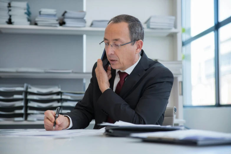 man sitting at table while talking on the phone