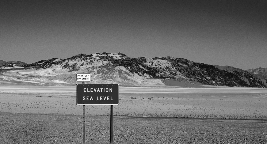 a road sign sitting on the side of a dry grass field