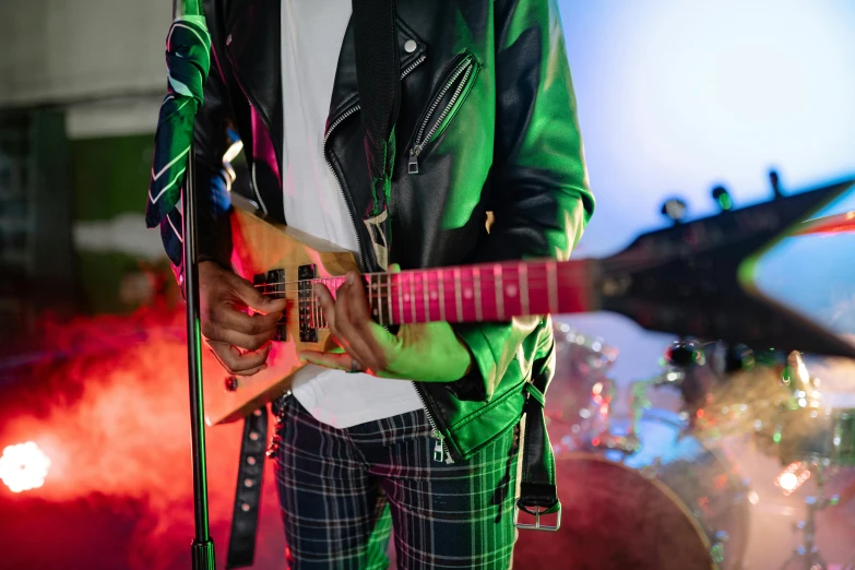 the man is holding a guitar and singing into his microphone