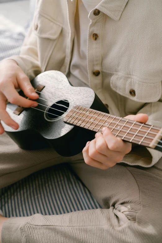 the person is playing the guitar while sitting down