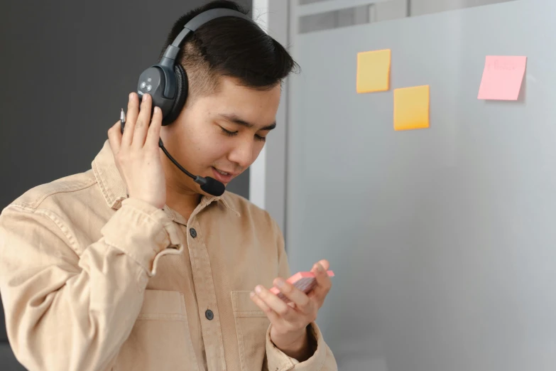 a man wearing a headset is standing by a wall