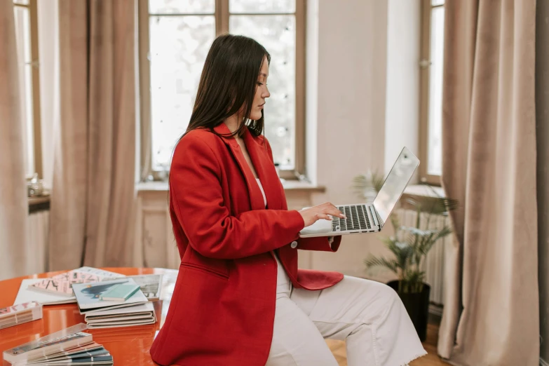 a woman in a red coat using a laptop computer