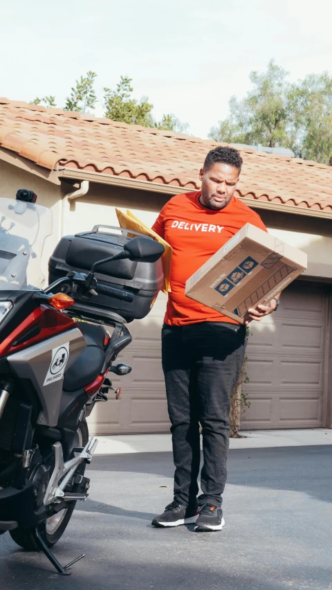 a man is holding some kind of box and a motorcycle