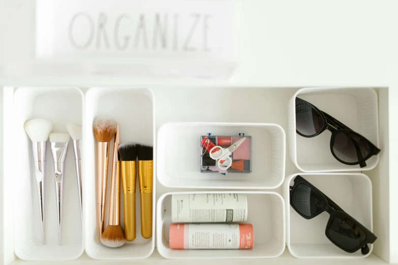 an organized drawer with makeup and accessories in white bins