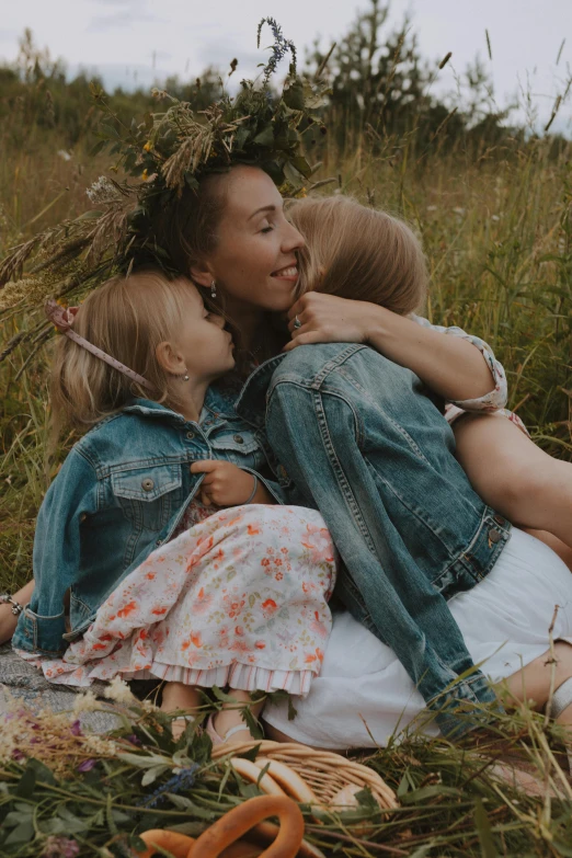 three young ladies hugging each other while laying in the grass