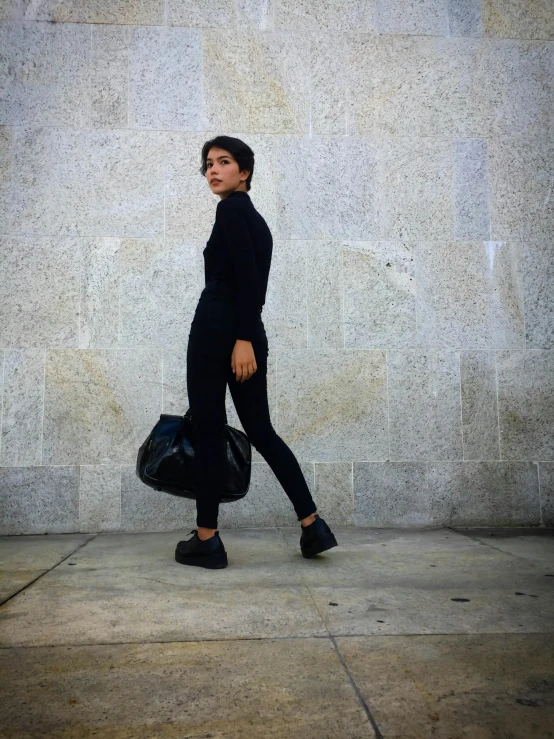 a woman is walking across a sidewalk carrying a bag