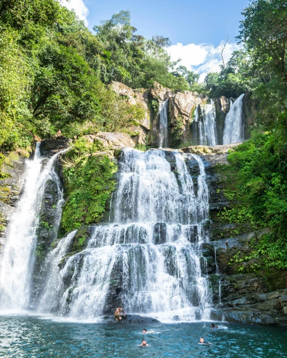 there are some people that is in the water by a waterfall