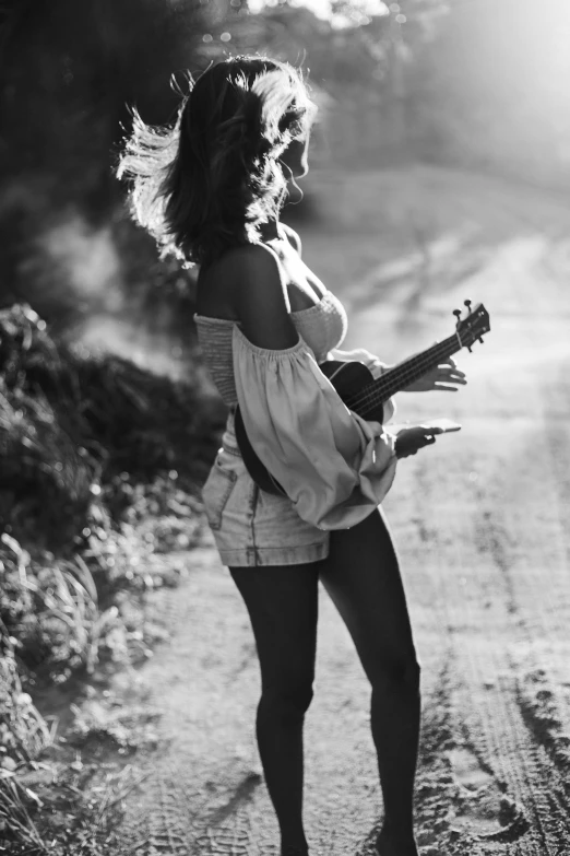 woman holding an acoustic guitar standing on the road