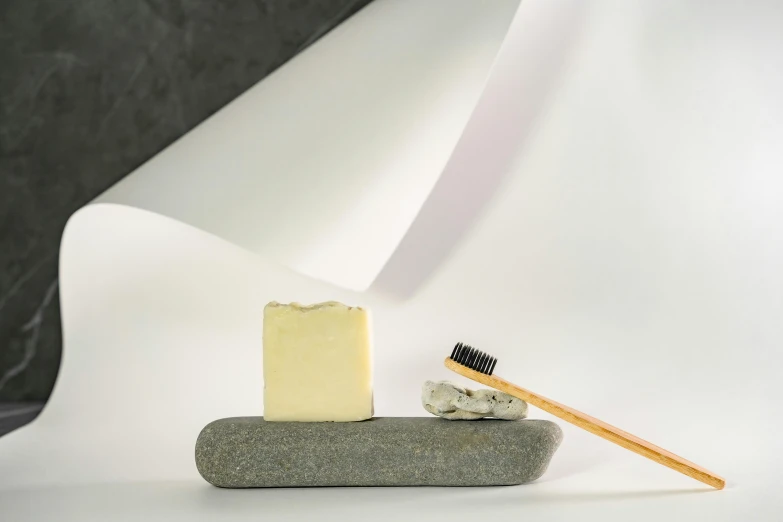 a piece of cheese sitting on top of a rock with a yellow toothbrush in it