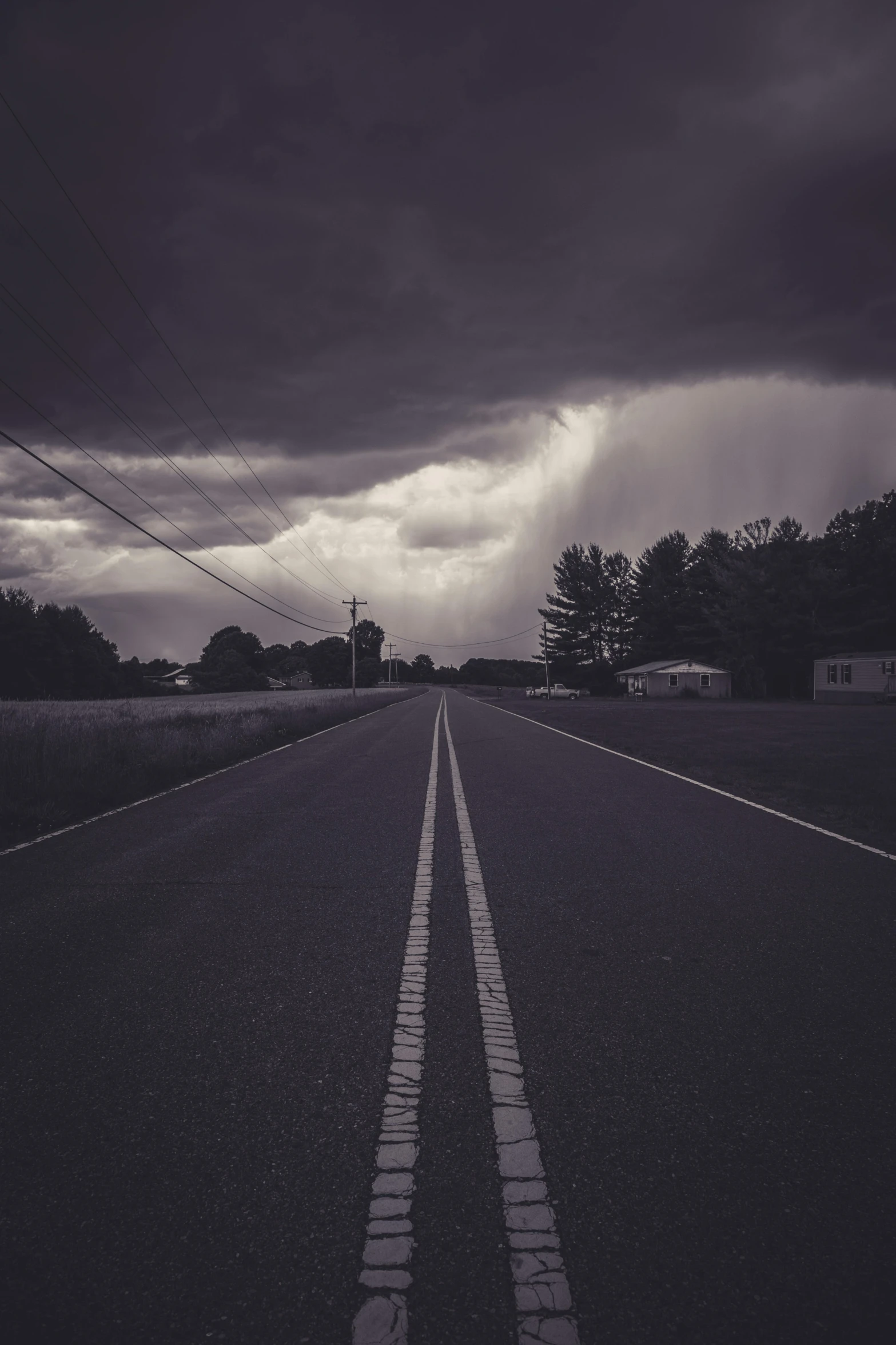 long straight road with storm clouds above it