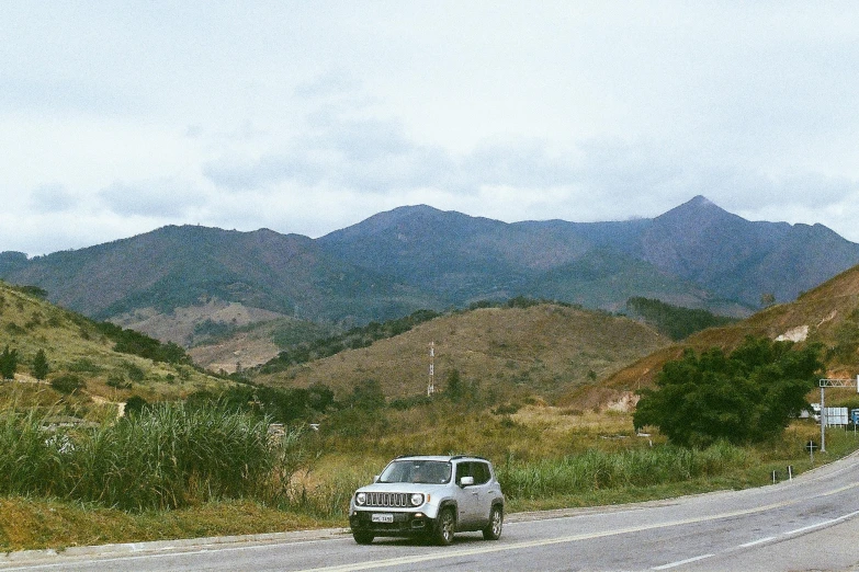 a grey truck driving down the side of a road