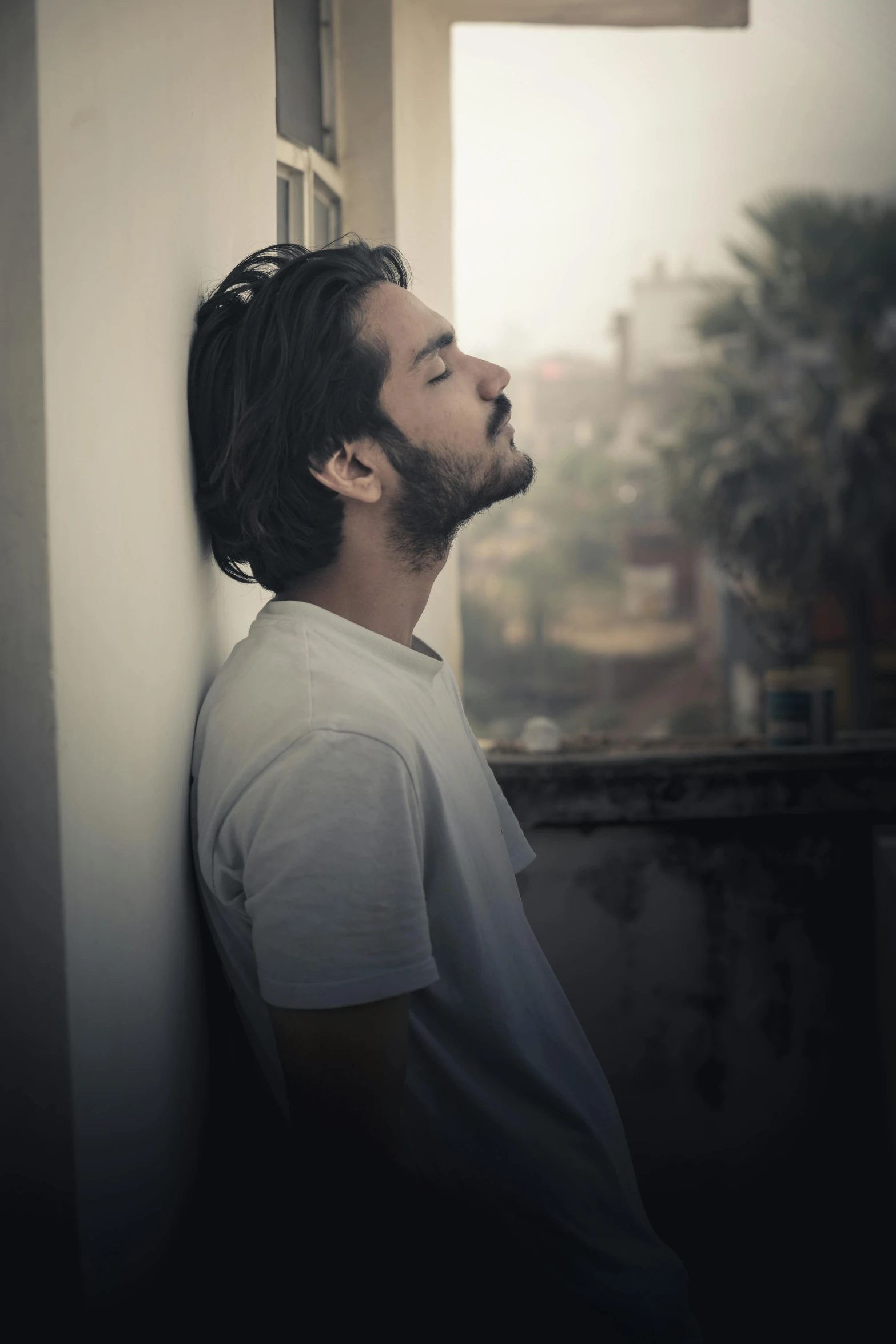 man looking up while standing in front of window