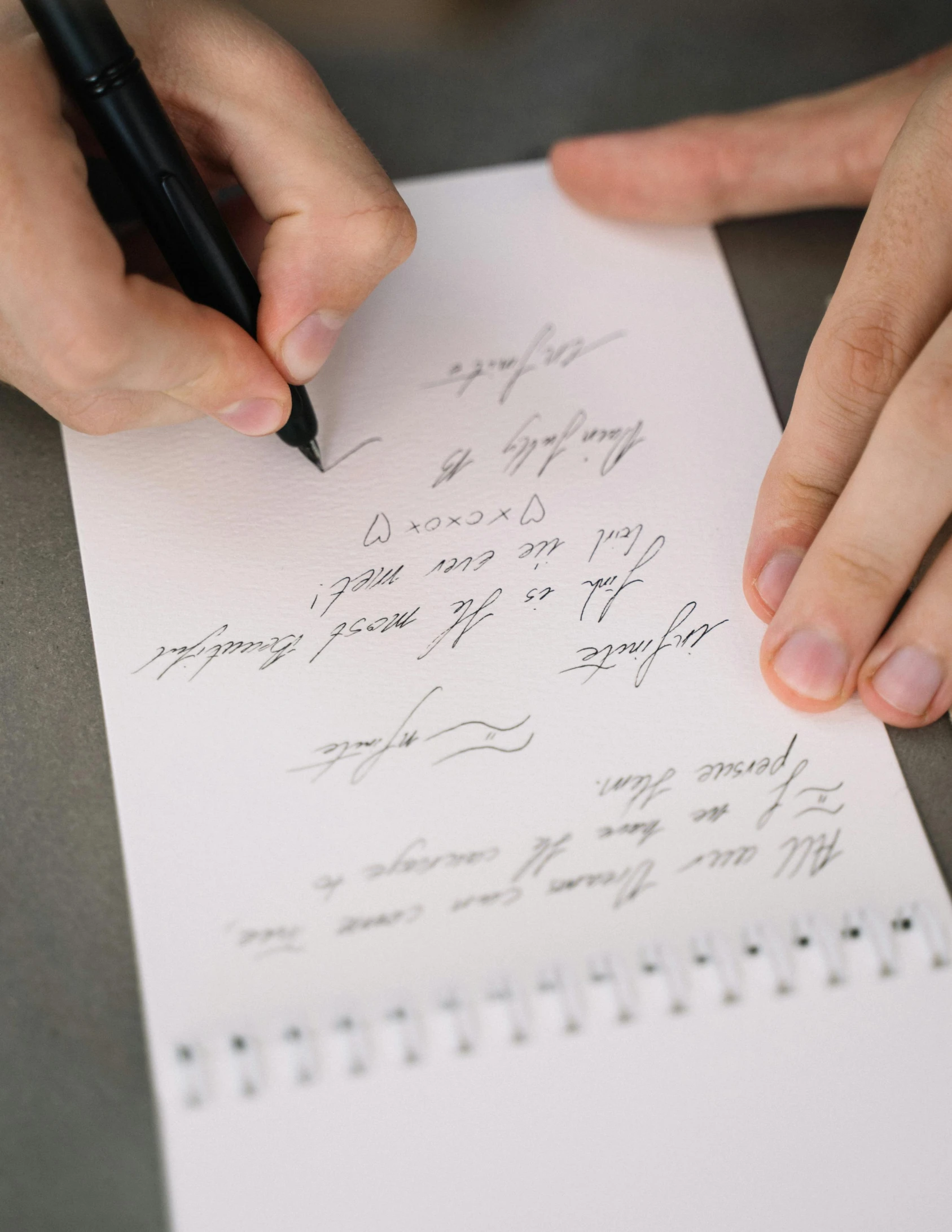 a hand is signing letters on white paper with fountain pens