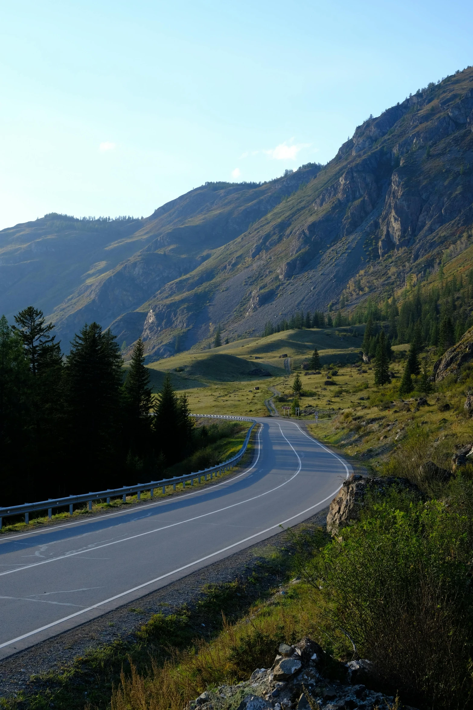 a winding highway with green hills in the background