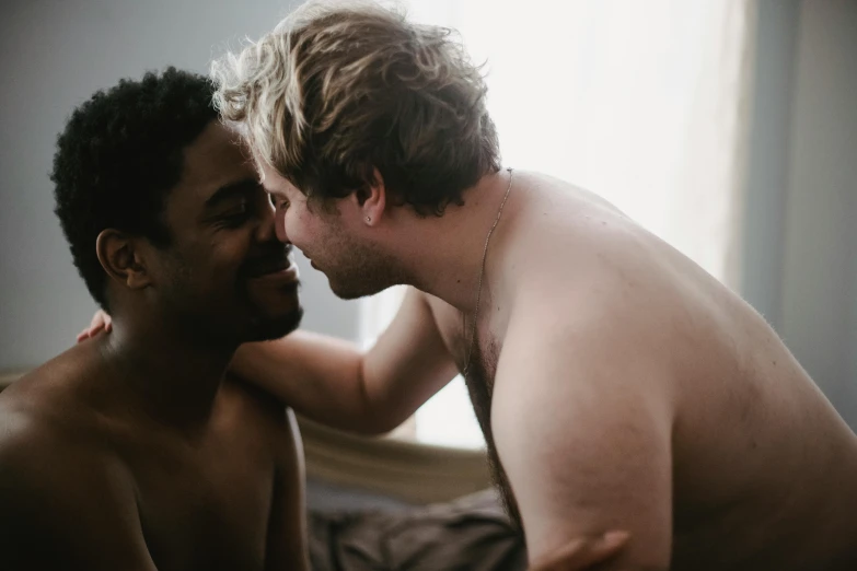 a shirtless man is playing with another person on his bed