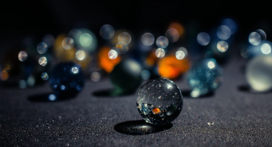 glass orb sitting on the ground next to other colored glass objects